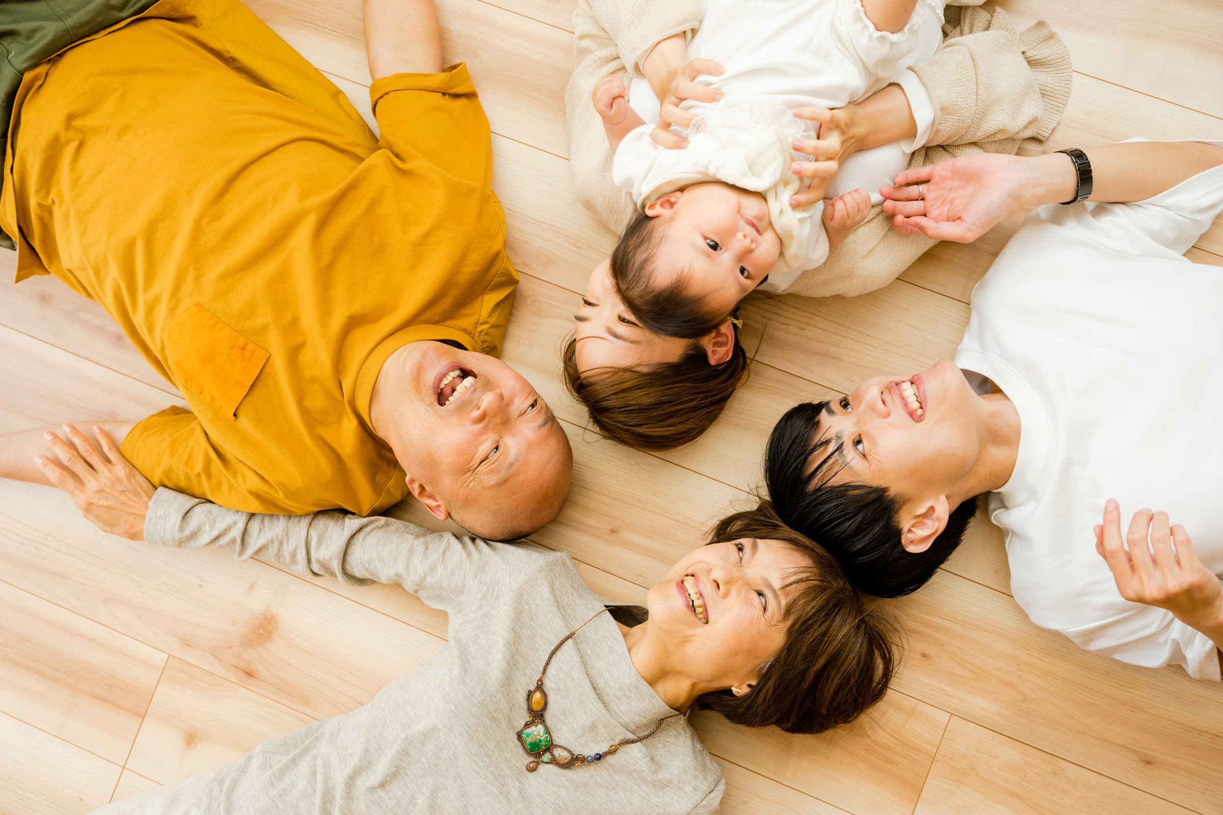 Five families of 3rd generation of babies, parents and grandparents who lie upwards on the floor